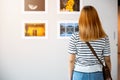 Asian woman standing she looking art gallery in front of colorful framed paintings pictures Royalty Free Stock Photo