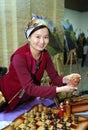 Asian woman standing at a table set with traditional Kazakh souvenirs showing them to visitors