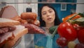 An Asian woman stands at an open refrigerator, with healthy and unhealthy products. The woman wondered what to choose Royalty Free Stock Photo