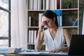 Asian woman stressed while working on laptop, Tired asian businesswoman with headache at office, feeling sick at work Royalty Free Stock Photo