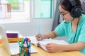 Asian woman writing notes at book learning online Royalty Free Stock Photo