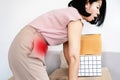 Asian woman suffering from stomach muscle pain after incorrect lifting heavy boxes