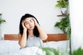 Asian woman suffering from headache after wake up in morning sitting in bed hand holding her pain head Royalty Free Stock Photo