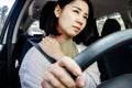 Asian woman suffering from neck and shoulder pain while driving behind the wheel of car ,
