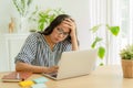 Asian woman suffering stress working on laptop in overworked. Tired businesswomen using computer and holding her hand on her templ