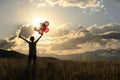 Asian woman on sunset grassland with colored balloons Royalty Free Stock Photo