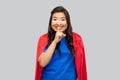 Asian woman in superhero cape making hush gesture