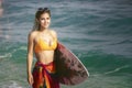 Asian woman with surfboard on hand on the beach