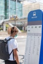 Asian woman with surgical face mask feel tired looking at bus stop information