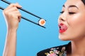 Asian woman with sushi eating sushi and rolls on a blue background Royalty Free Stock Photo