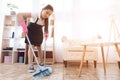 Asian woman sweeps floor while standing in room. Royalty Free Stock Photo