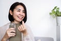 Asian woman taking probiotic supplement pill with a glass of water