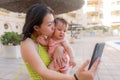 Asian woman taking selfie photo with her adorable baby girl - beautiful Chinese mother holding her little daughter and taking Royalty Free Stock Photo