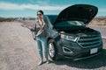 Asian woman talking on cell phone by a broken car Royalty Free Stock Photo