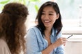 Asian woman talking with colleague sitting at desk indoors Royalty Free Stock Photo