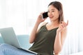 Asian woman talking on the phone while using laptop Royalty Free Stock Photo