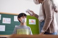 Asian Woman Teacher using digital thermometer checking temperature on Asian boy forehead Royalty Free Stock Photo