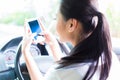 Asian woman texting while driving car