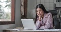 asian woman thinking hard concerned about online problem solution looking at laptop screen, worried serious asian Royalty Free Stock Photo