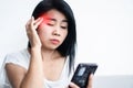 Asian woman tired her eyes having a headache and forcing eye to watch , reading mobile screen , social addiction concept