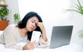 Asian woman tired her eyes and having headache working hard on laptop and watching mobile phone screen