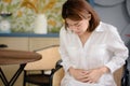 An Asian woman is touching her stomach due to suffering from stomach aches and undesired symptoms Royalty Free Stock Photo