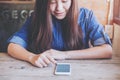 Asian woman touching and using smart phone with feeling happy while sitting in vintage wooden cafe Royalty Free Stock Photo