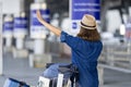 Asian woman tourist passenger is calling the pick up taxi at the airport terminal for transportation during her vacation travel