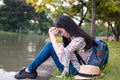 Asian woman tourists backpacker there is stress and fatigue. she has a sadness. during travel. at the waterfront public park. in