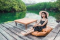 Asian woman tourists sitting and admiring the view river with mangrove forest. And the clear skies with beautiful clouds. Suitable