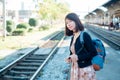 Asian woman tourists is standing on a backpack. Wait for the train to travel. On vacation