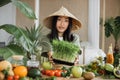 Asian woman in traditional conical hat making vegetable and fruit and microgreen sprouts salad