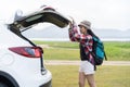 Asian woman travel camping on vacation. A girl open and close back door hatchback car white color on nature green view