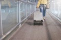 Asian woman traveler dragging carry on luggage suitcase at airport corridor walking to departure gates