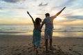 Asian woman traveler holding man`s hand and looking beautiful sunset on the beach, Couple on vacation in summer and freedom Royalty Free Stock Photo