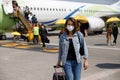 Asian woman traveler wearing protective hygiene mask holding bag walking in airport runway. Idea for a journey of new normal Royalty Free Stock Photo