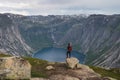 Asian woman traveller with backpack standing on rock and enjoying landscape of mountains and lake in Trolltunga mountain cliff Royalty Free Stock Photo