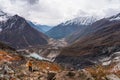 Asian woman trekker walking up on trail to Manaslu base camp in Samagaun village surrounded by Himalaya mountains range in Nepal