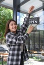 Asian woman turning open sign broad on the door glass and ready to service. Royalty Free Stock Photo