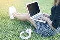 Asian woman typing Thai keyboard of laptop and sitting on green grass by relaxing Royalty Free Stock Photo