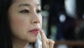 Asian woman use finger applying lip gloss moister on her lip while make up