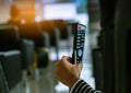 Asian woman use hand hold and press button on remote to control robotic massage chairs to relax head, shoulders, and back