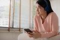 Asian woman uses her smartphone. uses headphones to listen to music Enjoying a song or listening to a meditation audio course Royalty Free Stock Photo