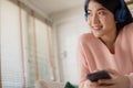 Asian woman uses her smartphone. uses headphones to listen to music Enjoying a song or listening to a meditation audio course Royalty Free Stock Photo