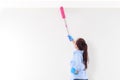 Asian woman uses a pink microfiber duster to clean her ceiling