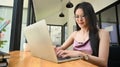 An Asian woman is using a computer laptop while sitting at the wooden working desk Royalty Free Stock Photo