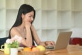 An Asian woman is using a computer laptop while sitting at the wooden working desk Royalty Free Stock Photo