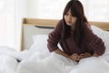 Asian woman is using her hands to hold her stomach because she has a stomach ache in bed room. Health care concept Royalty Free Stock Photo