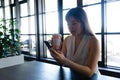 Asian woman using her phone and holding a mug Royalty Free Stock Photo