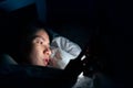 Asian woman using mobile phone on the bed in dark bedroom, Can not sleep suffering from insomnia Royalty Free Stock Photo